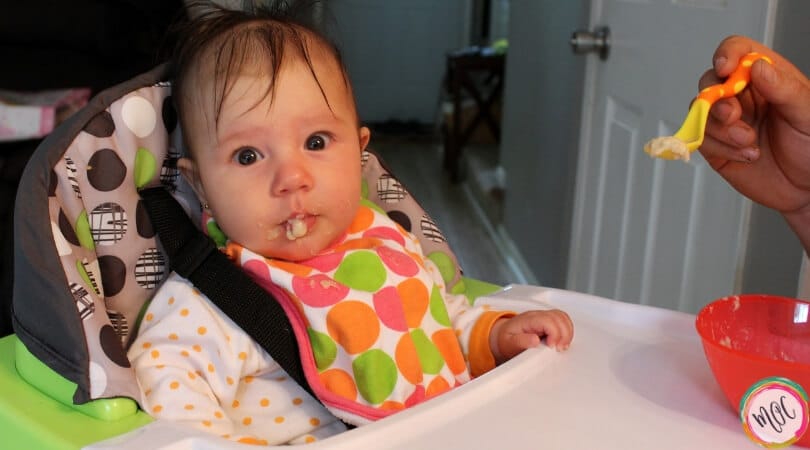 Knowing When a Baby Is Ready to Start Solid Foods. Baby eating solid foods while being spoon fed.