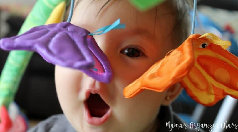 Baby having awake time with purple and orange butterfly hanging down from playmat