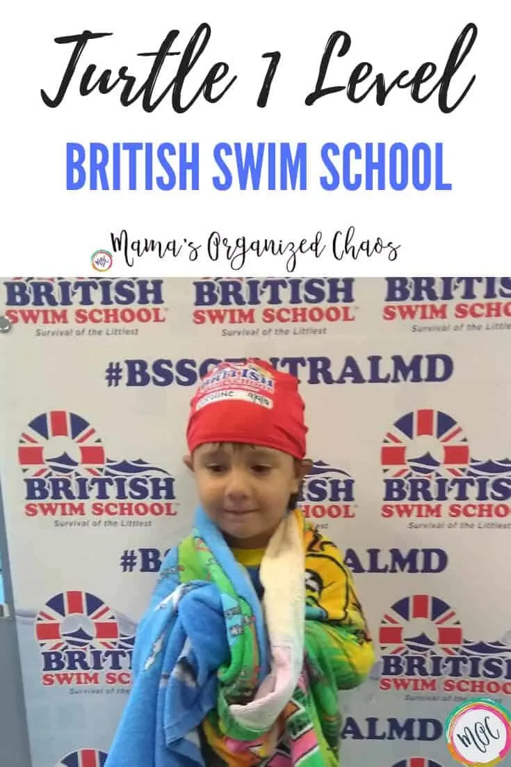 Graduation picture from minnow level to turtle 1 level in british swim school. Girl has her new red swim cap on standing in front of BSSCENTRALMD sign.