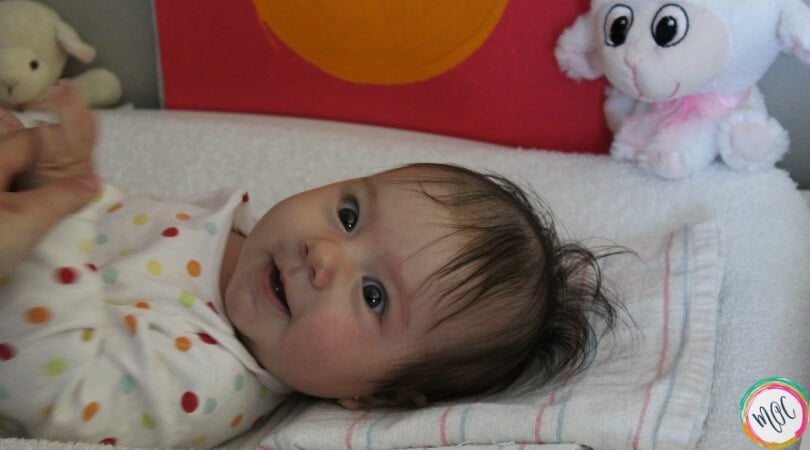 What is the Babywise Eat Wake Sleep Cycle? Baby lying on changing table with polka dot onesie on smiling. Just woke up from nap and is being changed. Will eat next as a part of the eat wake sleep cycle.