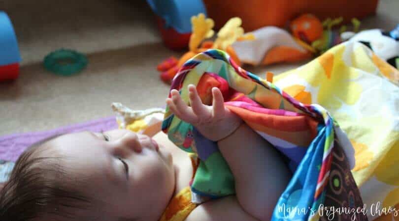 Baby lying on blanket looking at a soft book. Some of our favorite products.