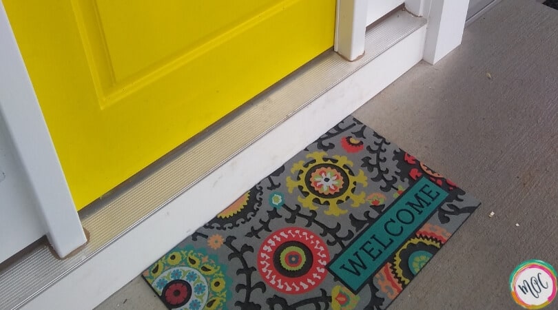 yellow door with colorful welcome mat