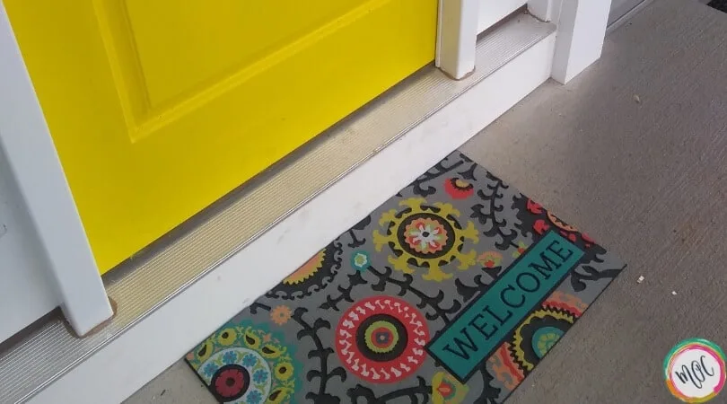 yellow door with colorful welcome mat