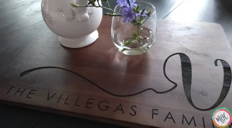 cutting board with "the villegas family" written, and purple flowers with a white vase
