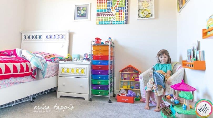 4 year old girl sitting in her colorful room reading a book