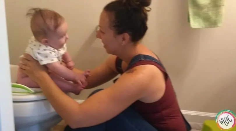 6 month old being held on the toilet
